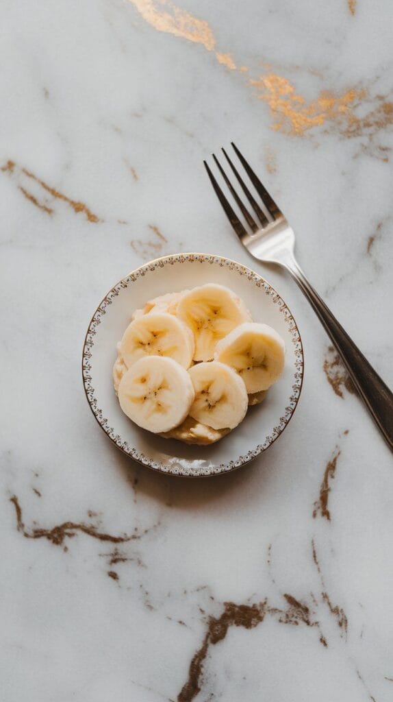 a small white plate with mashed ripe bananas, showing soft texture and a fork beside them