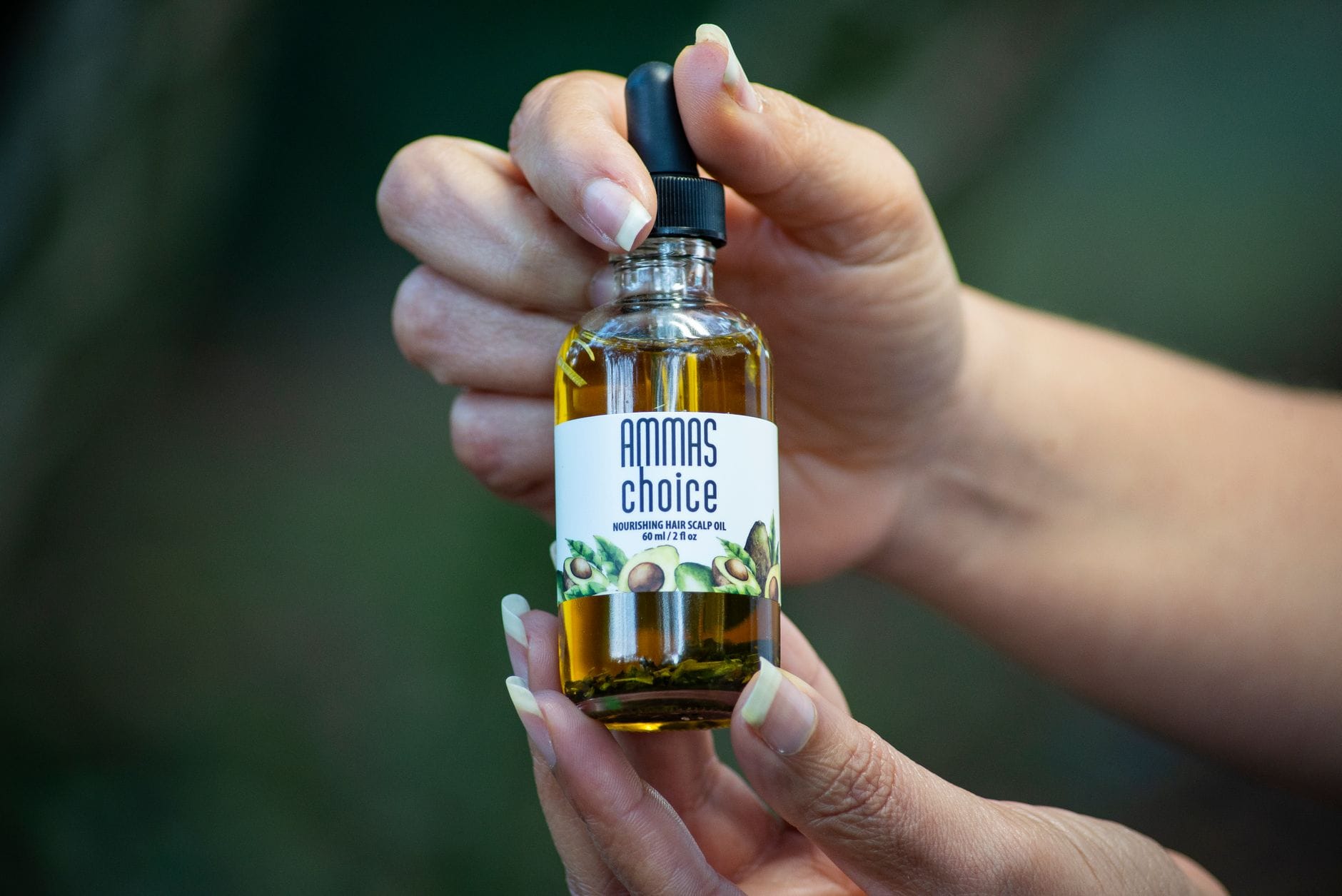 Hands working oil into the scalp along a dark hair part