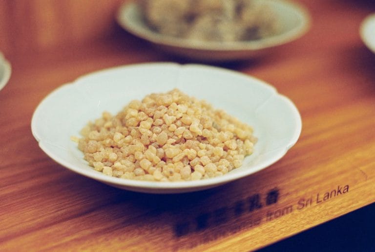 Golden translucent frankincense resin pieces piled on a dark stone surface