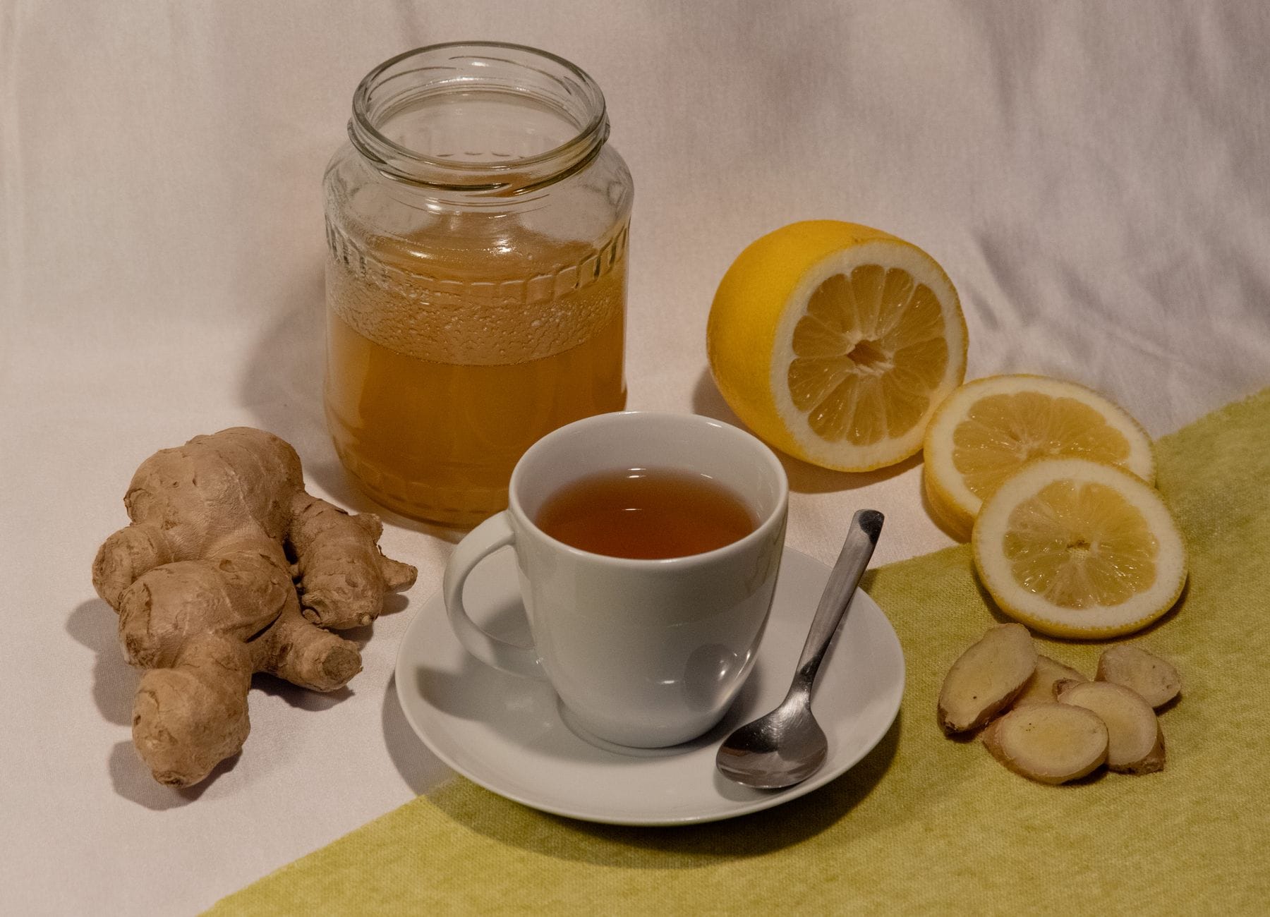 Steaming mug of ginger tea with honey and lemon slices on a wooden table