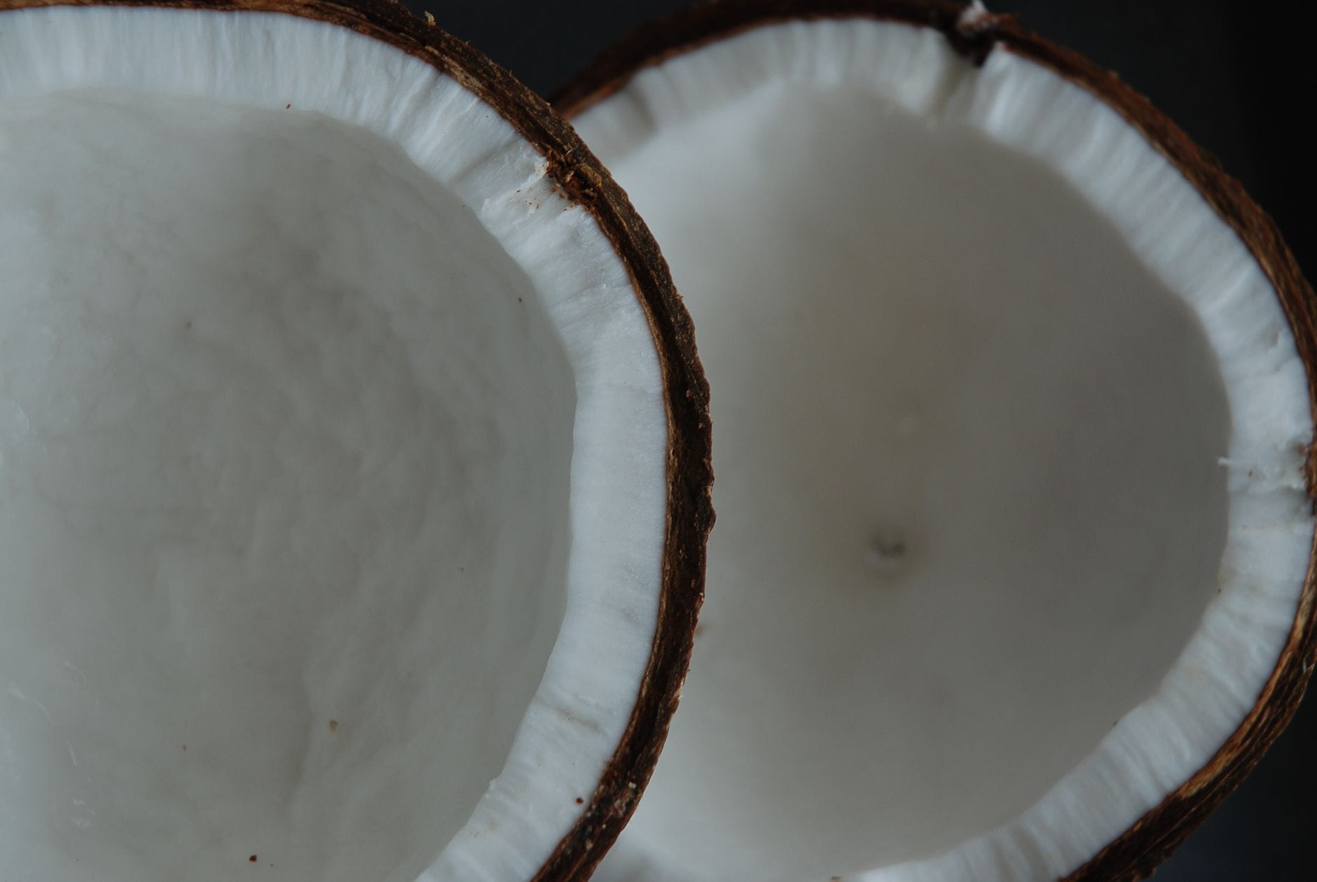 Split coconut halves with white flesh on a wooden board