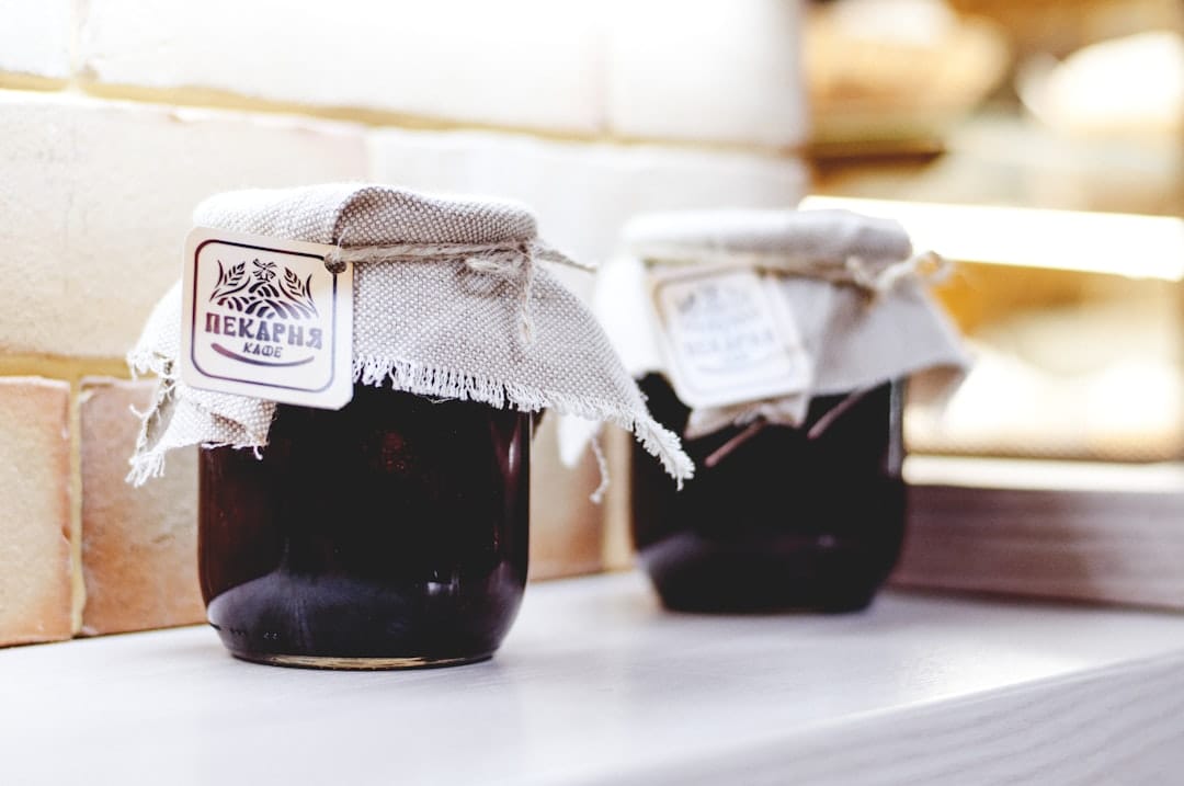 Deep violet yam jam in a glass jar with a spoon resting beside it