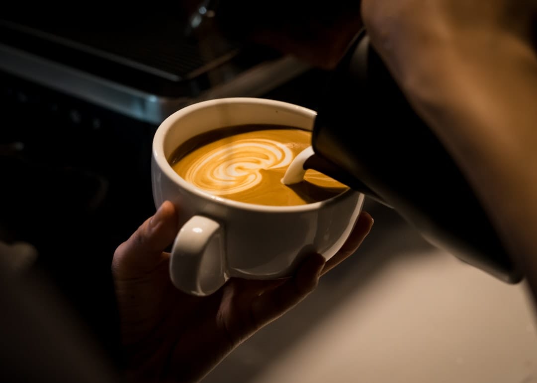 Dark coffee in a mug with cream swirling on the surface