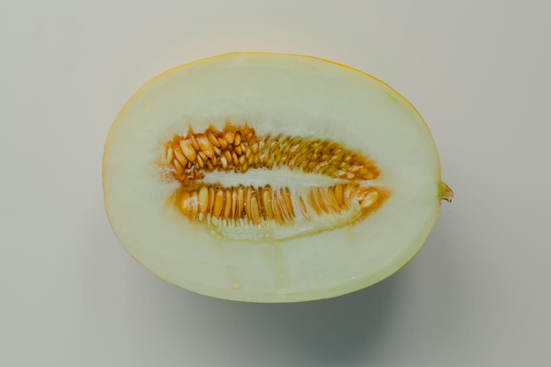 Pale green honeydew wedges cut open on a wooden board with seeds visible