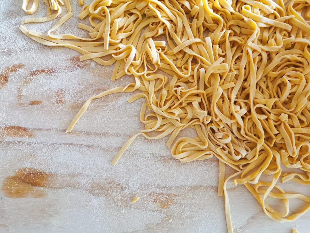 Ribbons of fresh pasta dusted with flour on a wooden board