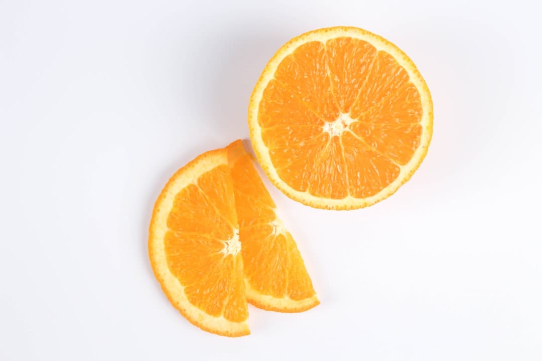 Halved oranges and bright citrus slices arranged on a wooden board