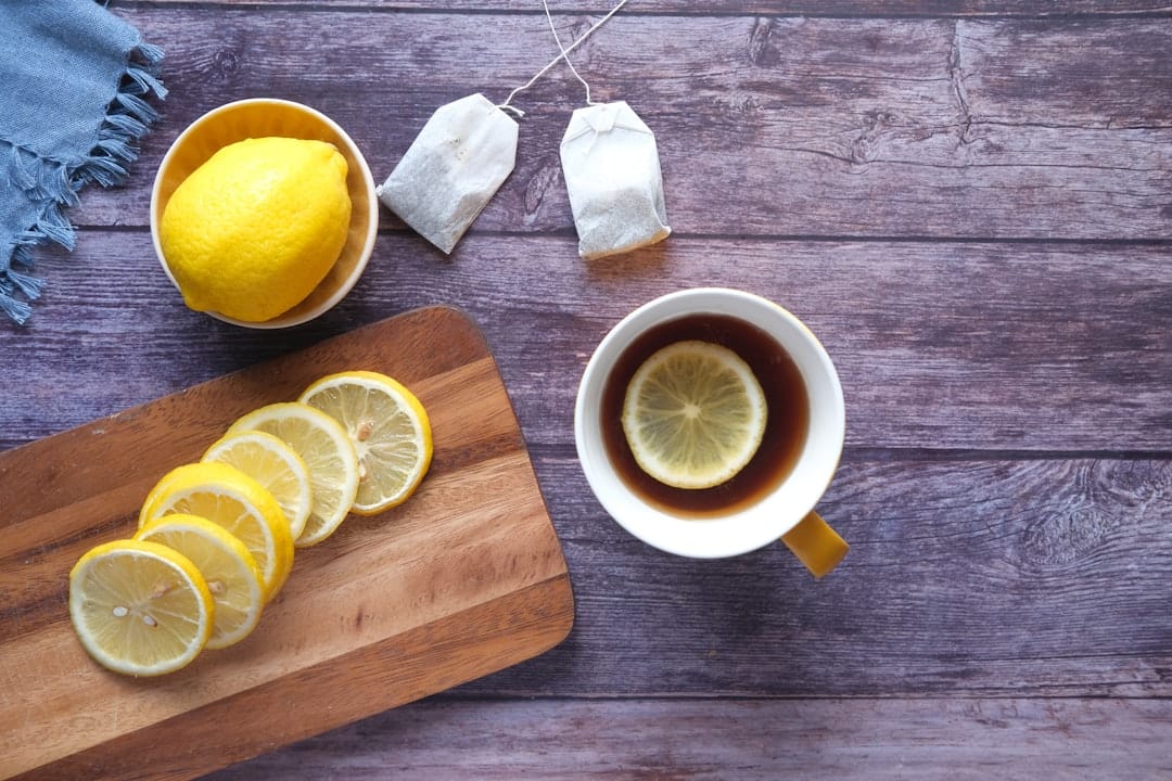 Cup of tea with lemon slices and a jar of honey on a wooden table