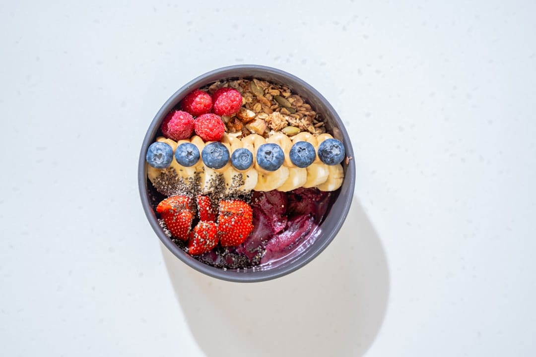 Purple berry smoothie bowl topped with shredded coconut and fresh raspberries
