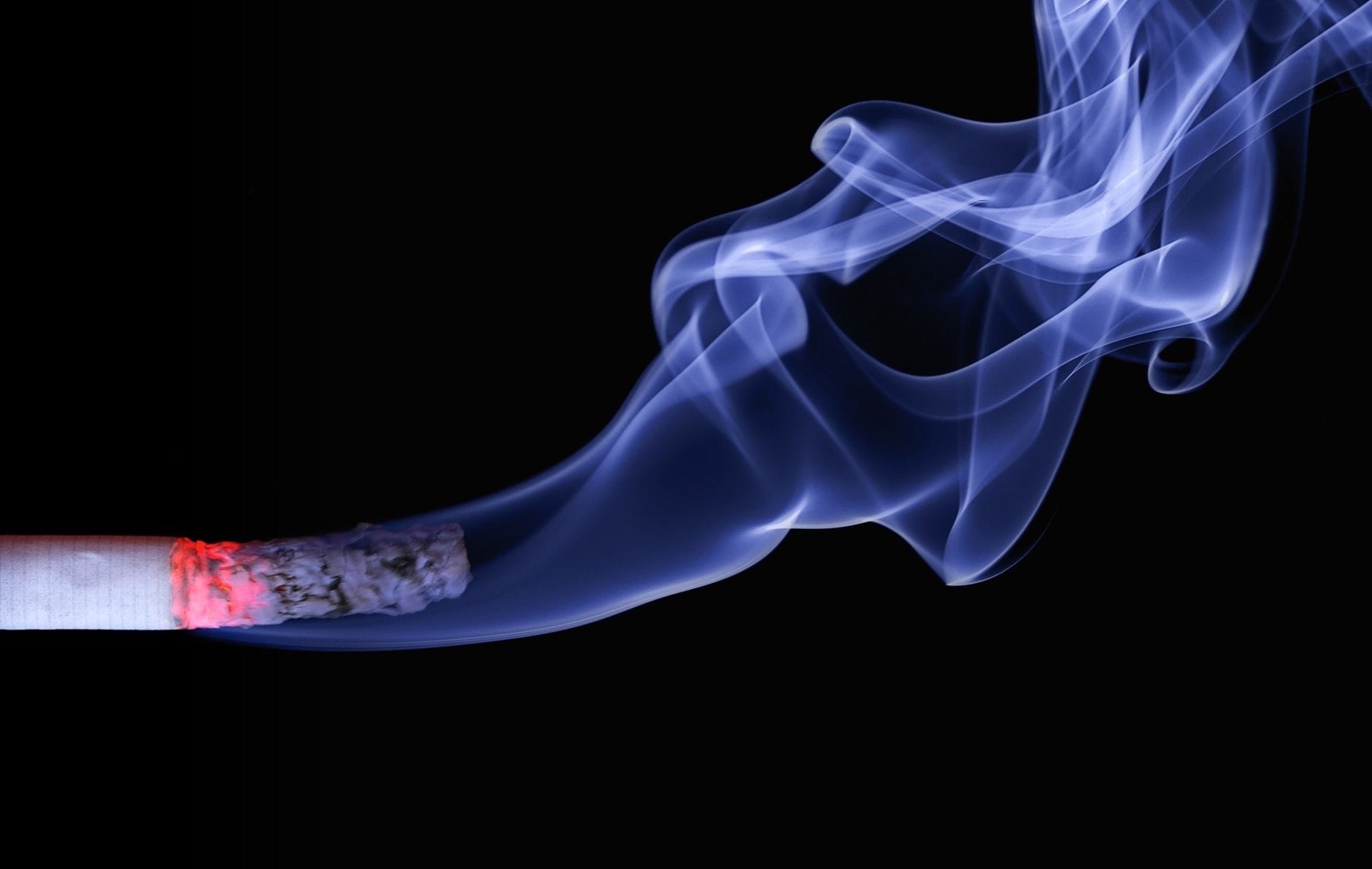 A lit cigarette resting on an ashtray with rising smoke