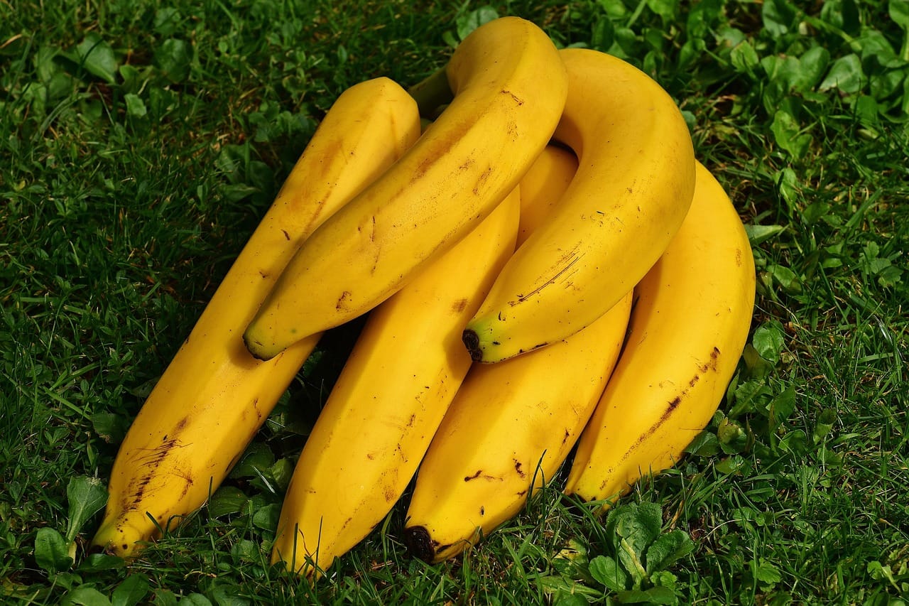 A bunch of yellow bananas resting on a rustic wooden surface