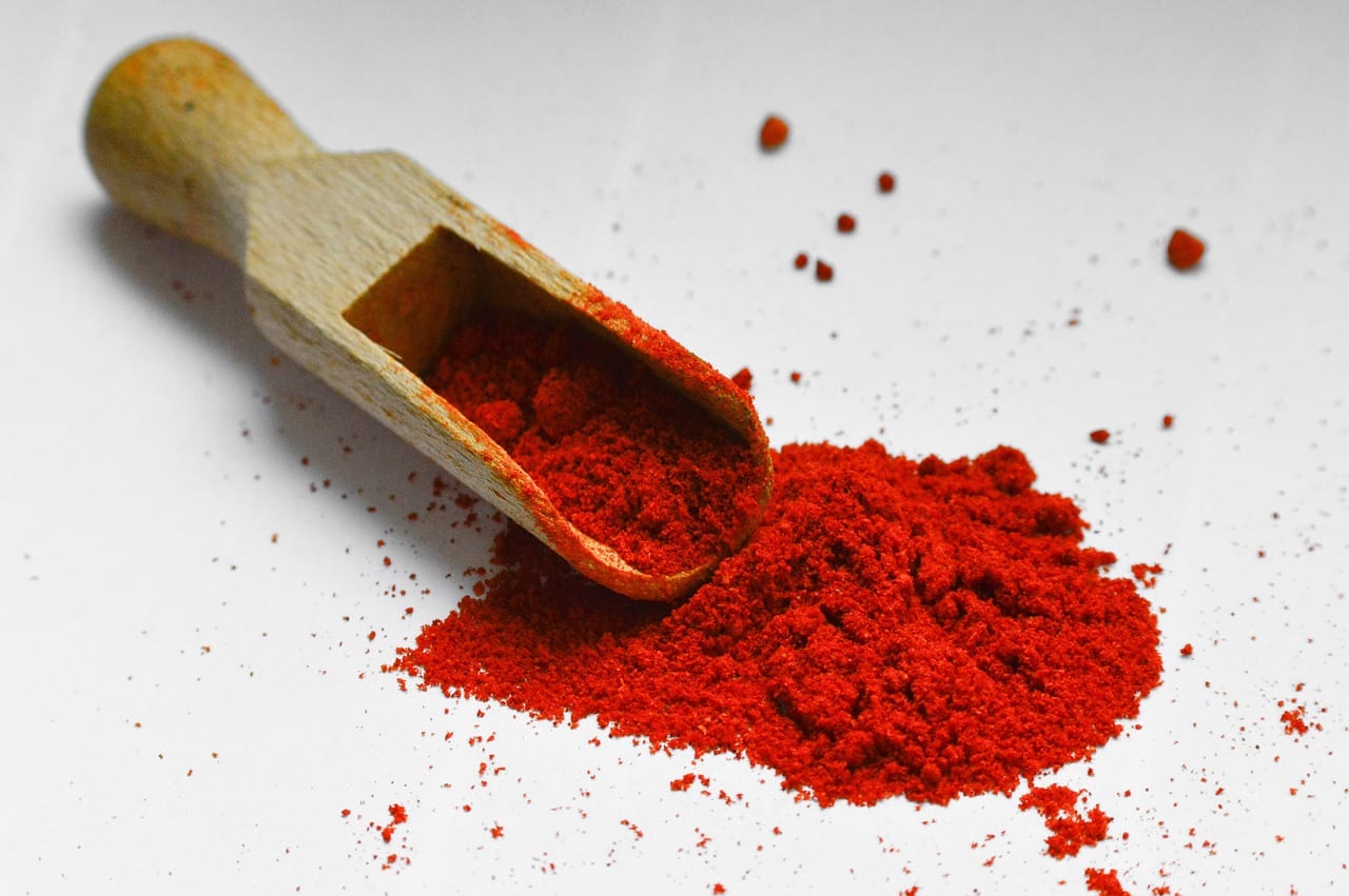 A measuring scoop filled with pale supplement powder on a counter