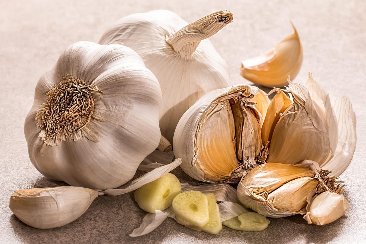 Whole and peeled garlic cloves resting on a wooden board