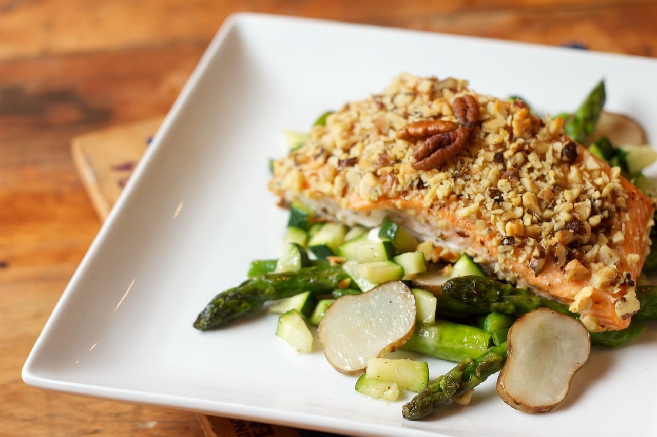 Sliced grilled chicken breast on a white plate garnished with herbs