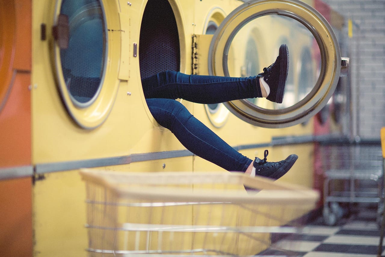 Hands loading dirty clothes into a front-loading washing machine