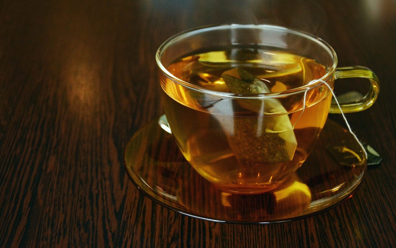 Steam rising from a clear glass cup of golden herbal tea