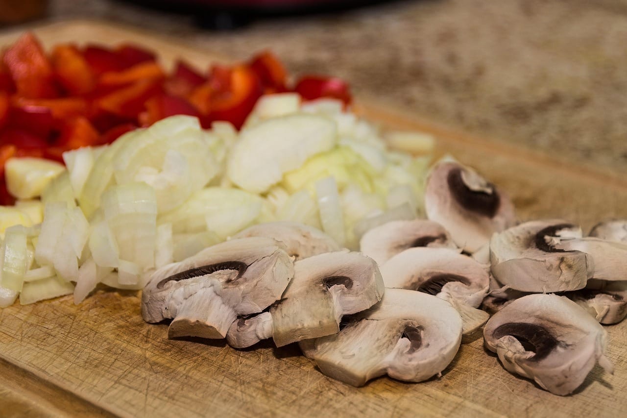 Thin pale slices of bamboo shoot arranged on a wooden cutting board