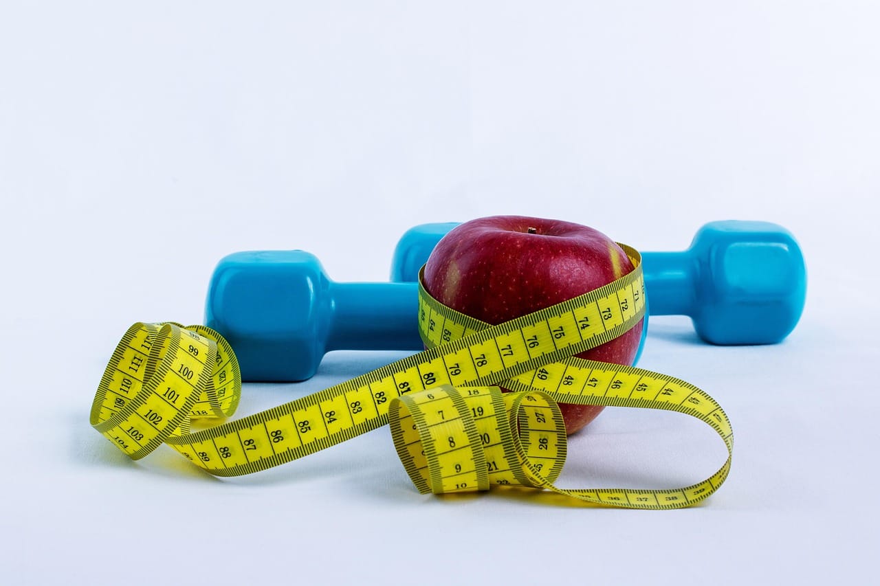A cloth measuring tape wrapped around a small dumbbell on wood