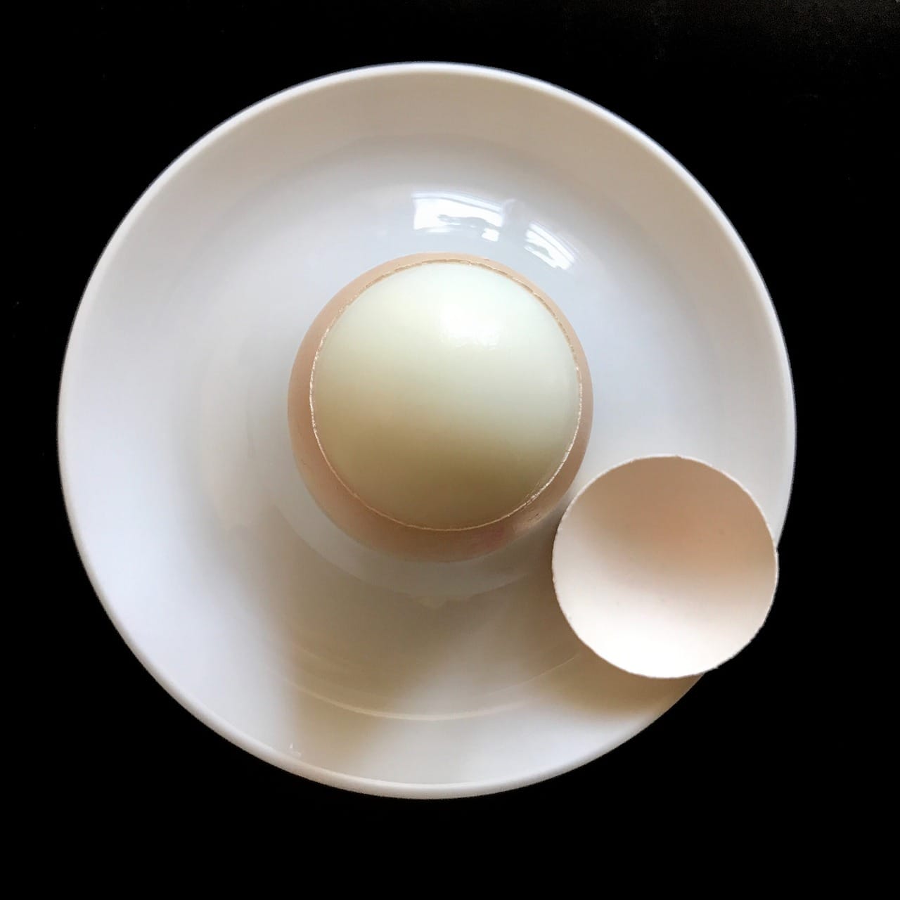 Sliced hard-boiled eggs arranged in a small white bowl on a table