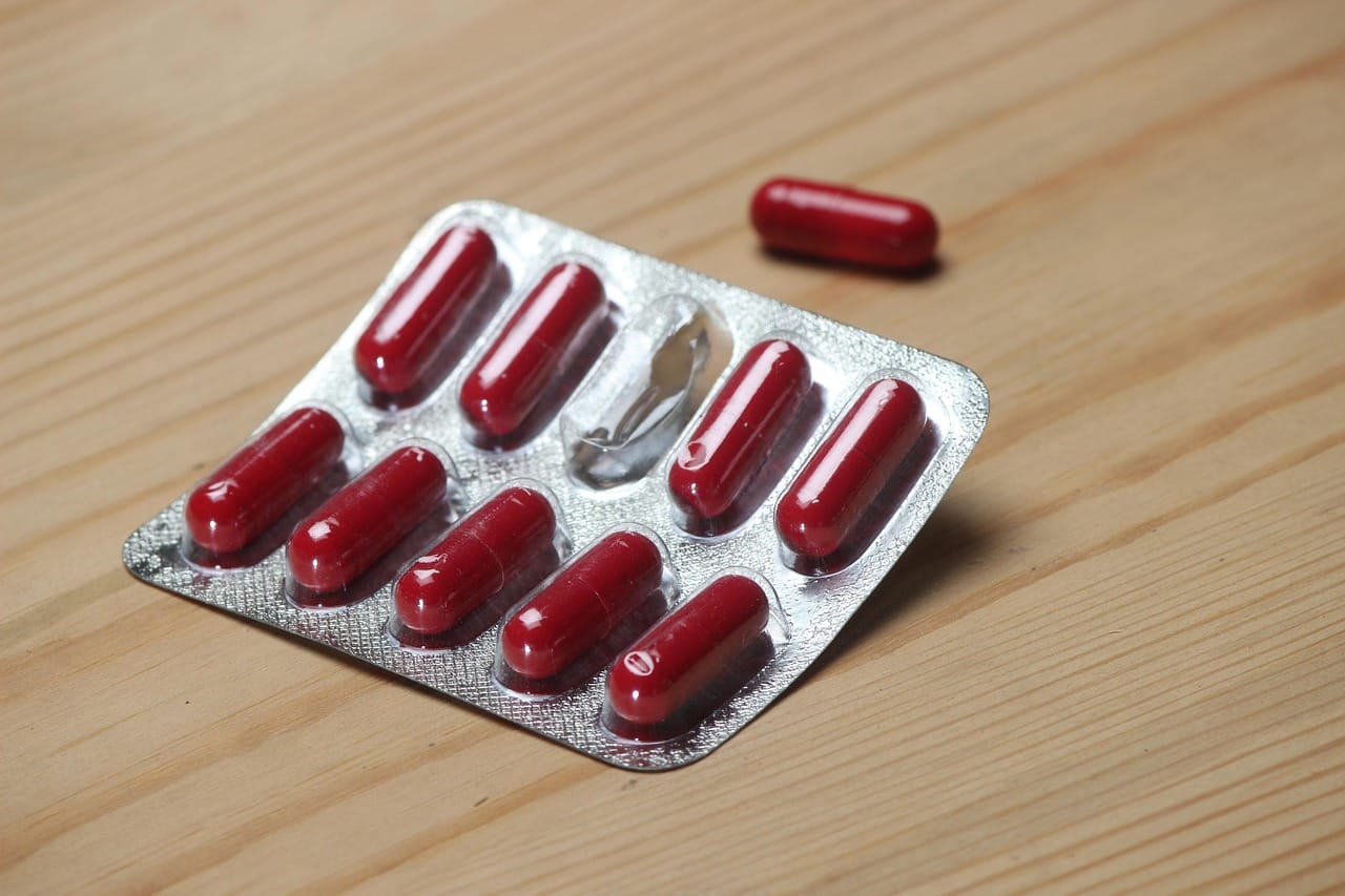Hand holding a blister pack of white antibiotic tablets