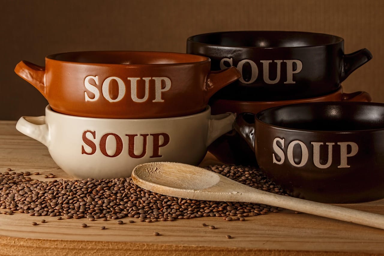 Wooden bowl filled with cooked brown lentils on a rustic table