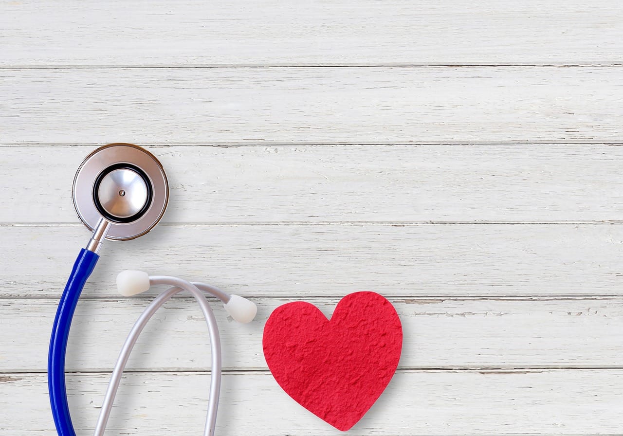 A wooden heart shape resting beside a doctor's stethoscope