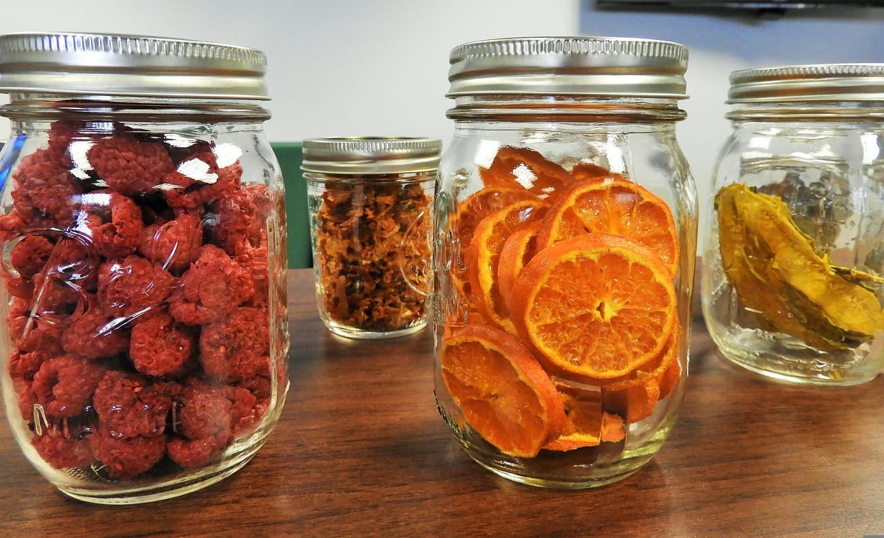 Glass jars of nuts, seeds, and dried spices lined on a shelf