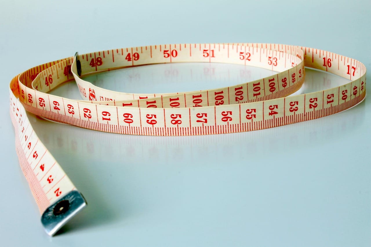A cloth tape measure wrapped around a bathroom weight scale