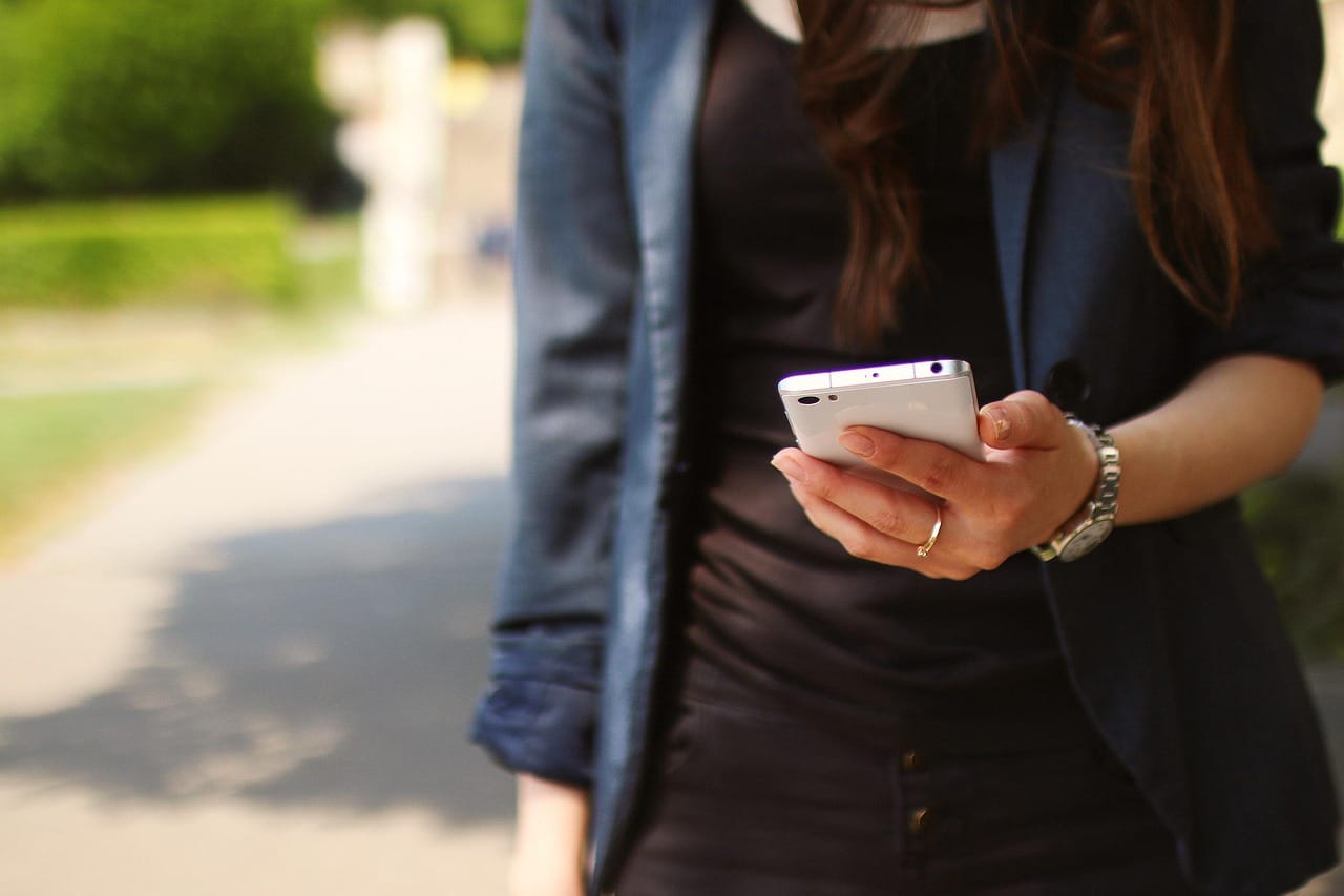 A person looking down at a phone held low in both hands