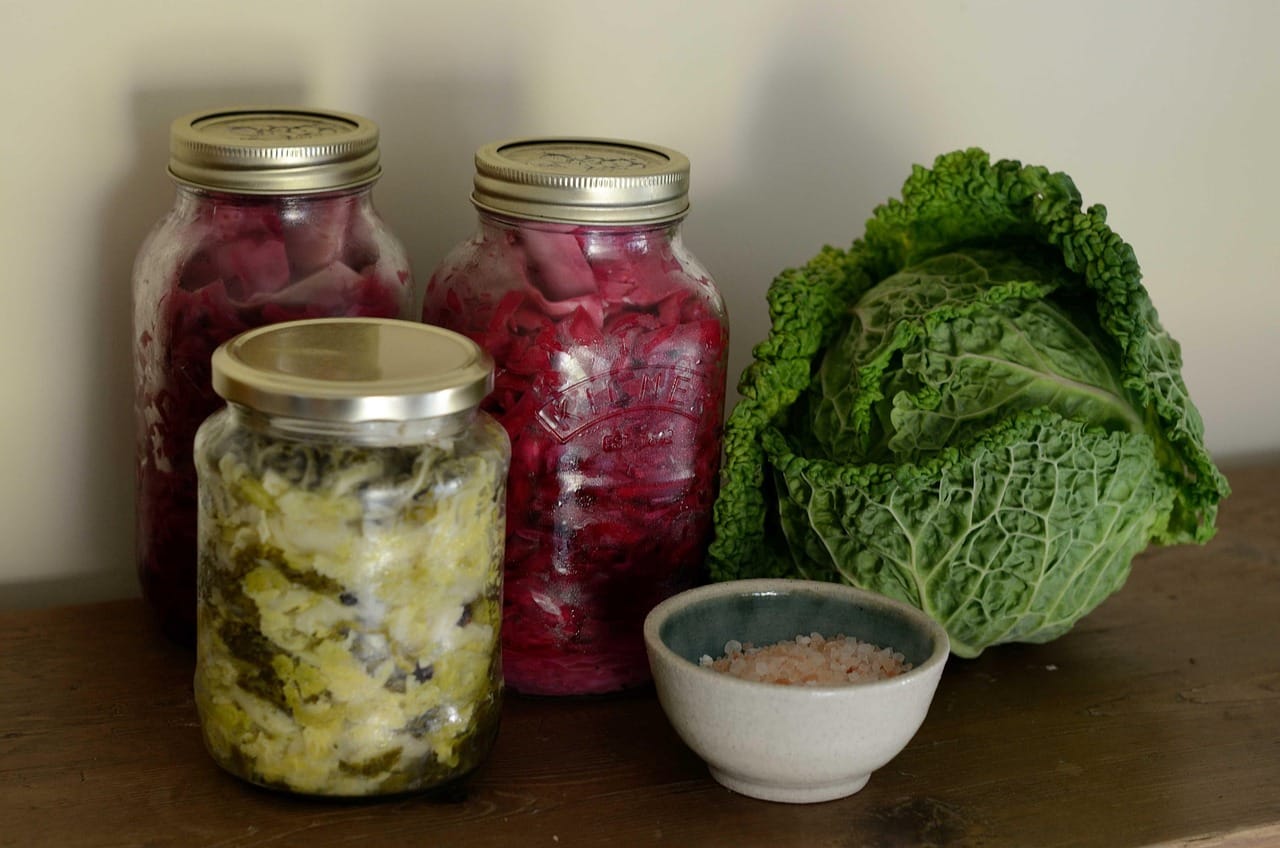 Glass jar packed with fermented shredded cabbage sitting on a wooden counter