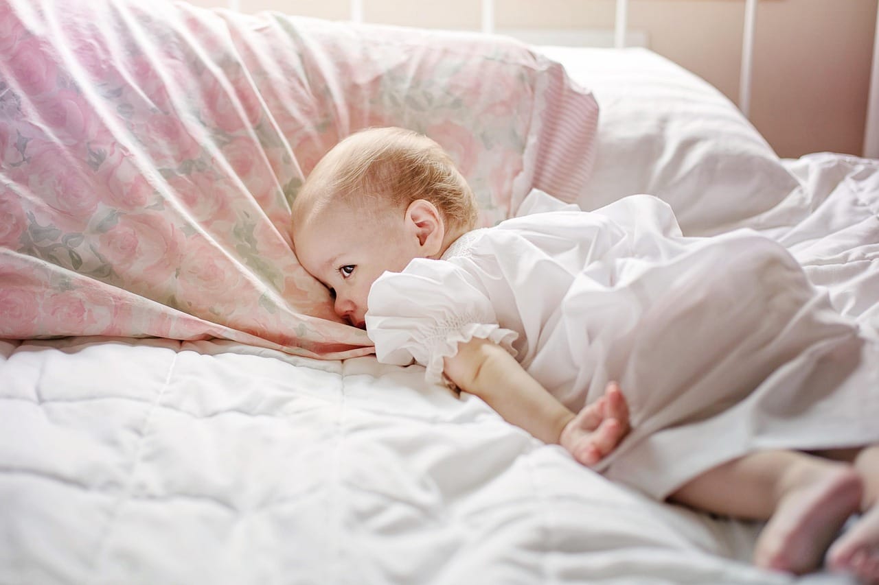 A person resting peacefully under soft white sheets in dim light