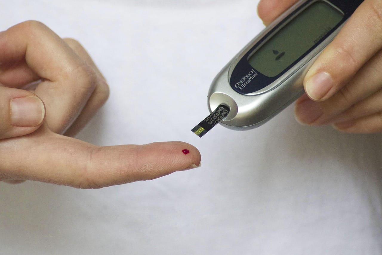 A person checking blood sugar with a handheld glucose monitor