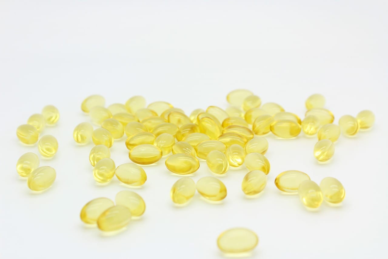 Golden fish oil capsules spilling from a small glass bottle
