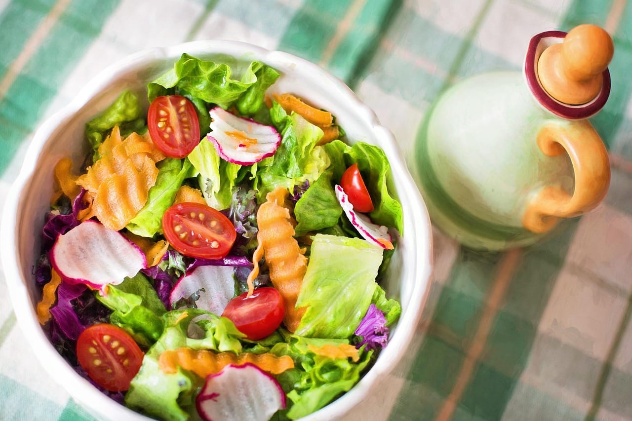 a colorful leafy salad topped with olives and sliced vegetables