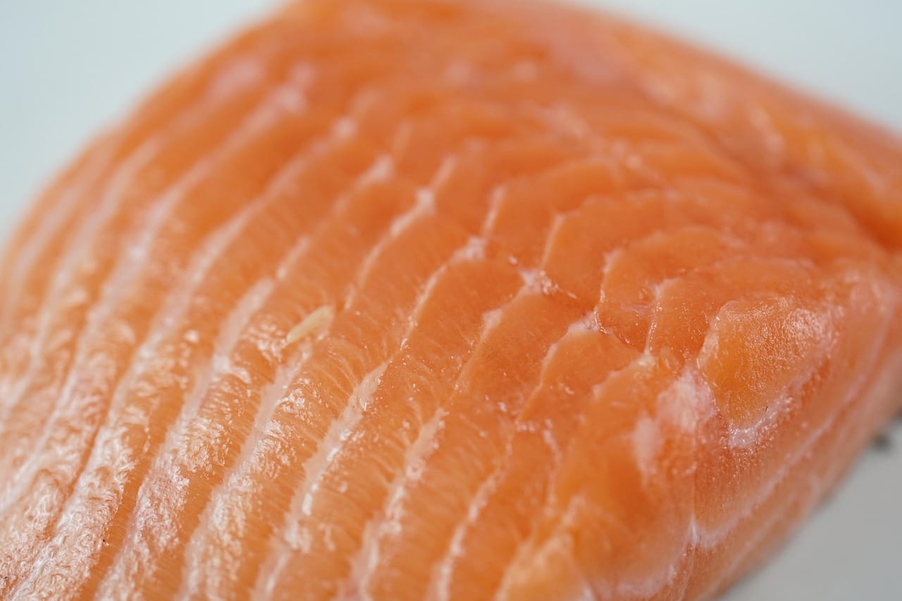 Raw salmon fillet on a wooden cutting board with lemon