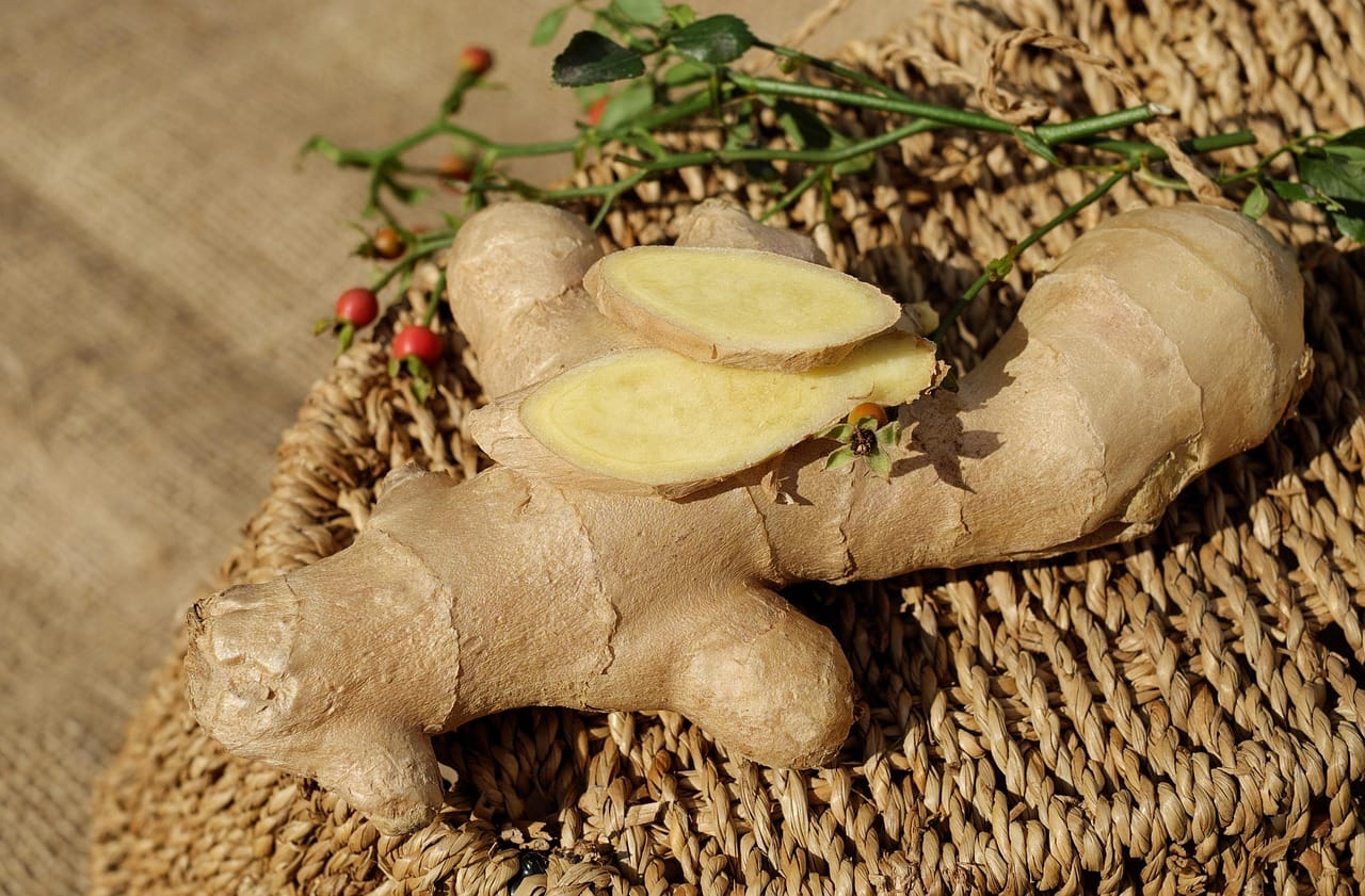 Whole and sliced turmeric and ginger roots on a wooden board