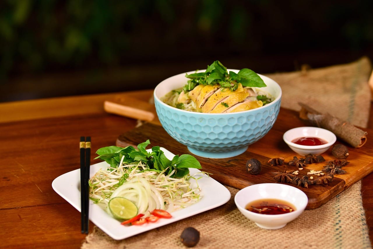 Steaming bowl of clear chicken soup with sliced bamboo shoots and mushrooms