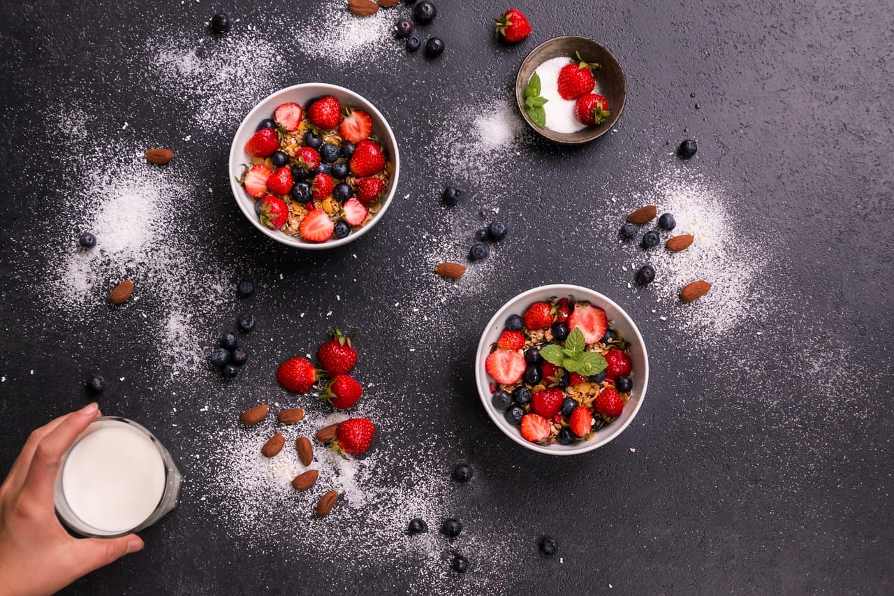 A tall glass of almond milk with scattered almonds nearby
