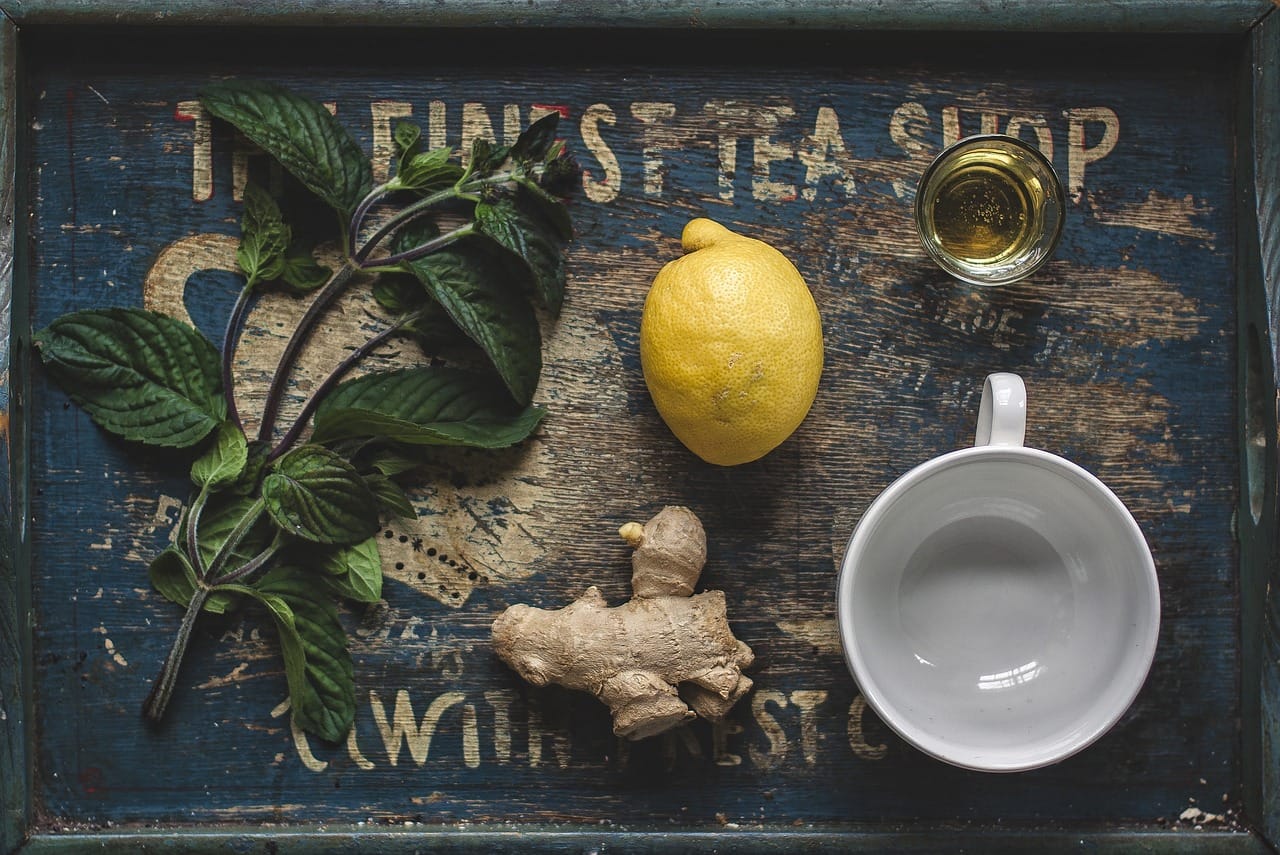 A steaming mug of tea with lemon slices and a spoonful of honey nearby