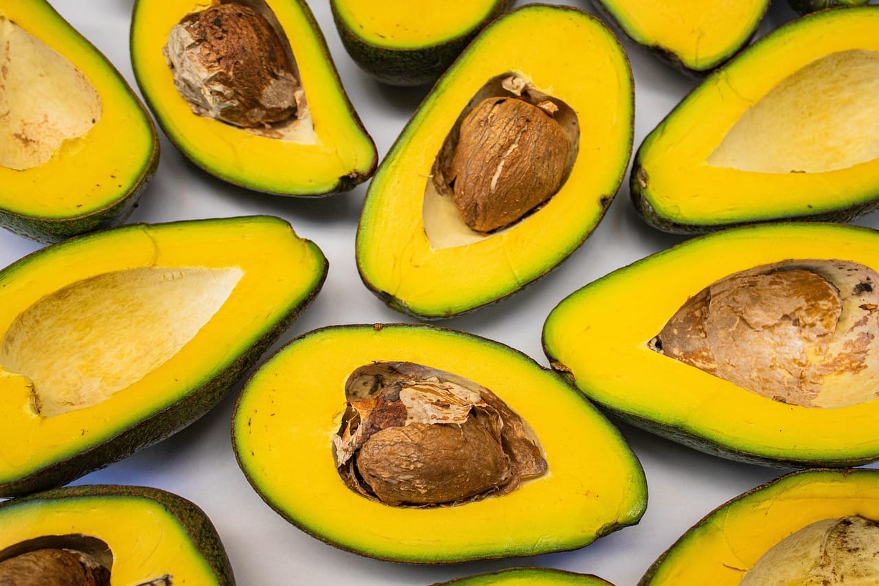 Halved avocados showing green flesh on a rustic wooden board