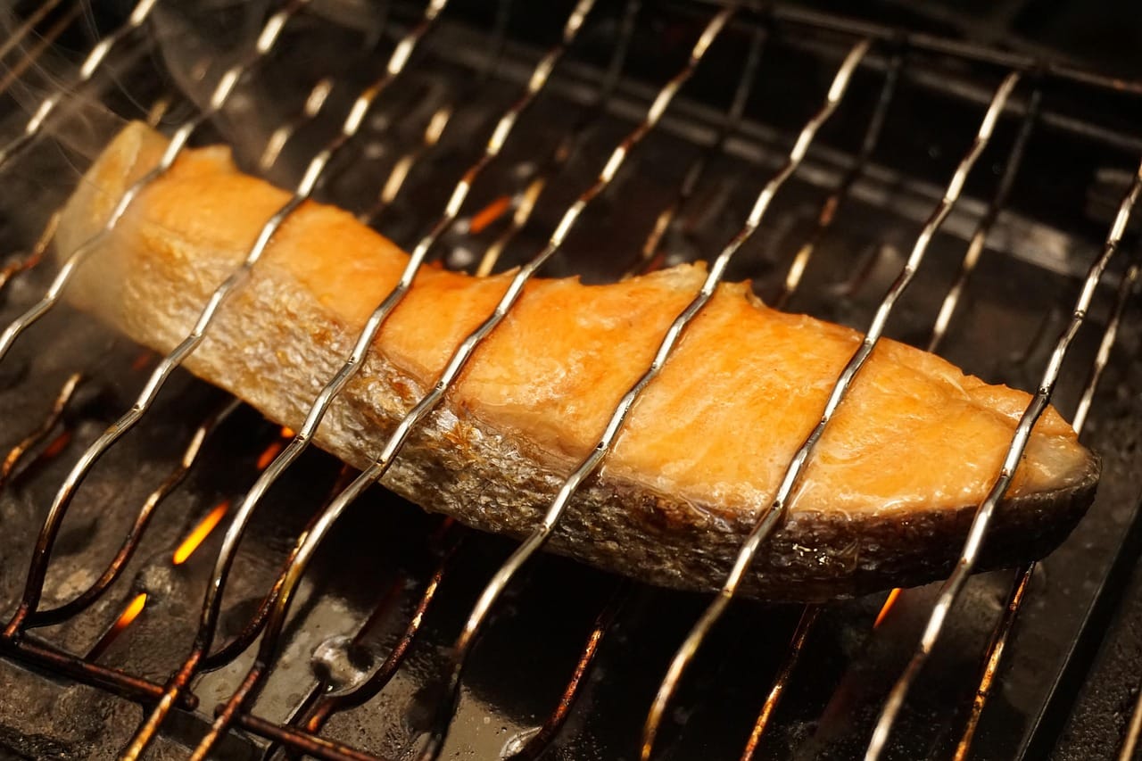 A seared salmon fillet plated with roasted asparagus and lemon wedges
