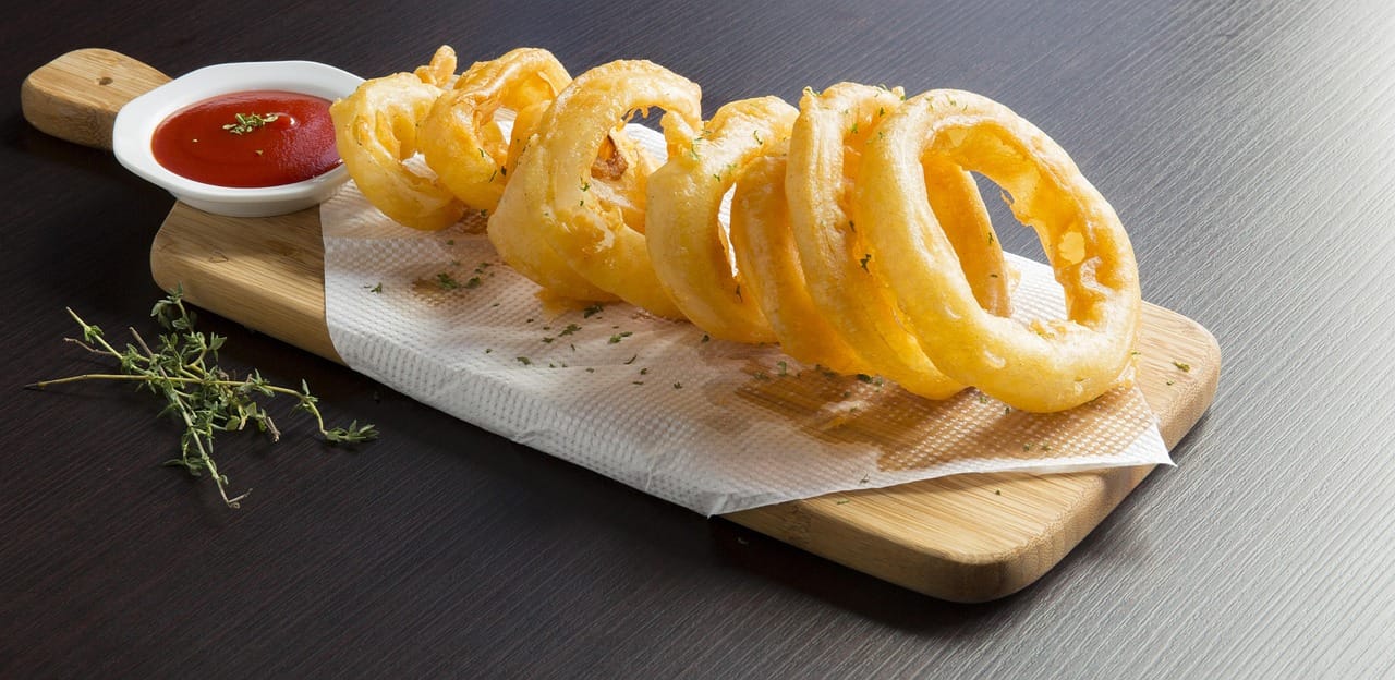 Golden crispy onion rings piled high in a wire basket