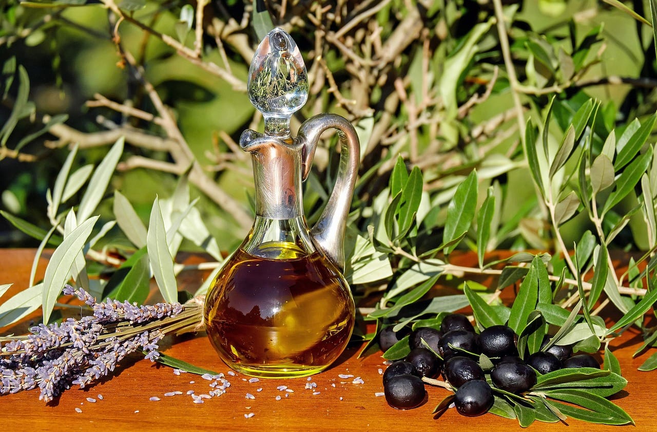 Amber dropper bottle of golden oil beside dried seeds on a wooden surface