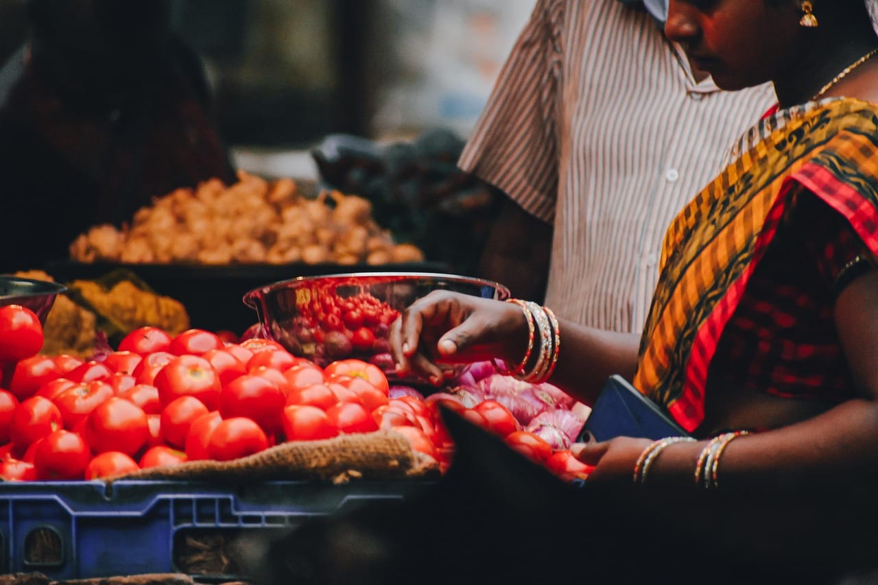 A woman holding a bunch of bananas at a market produce stand
