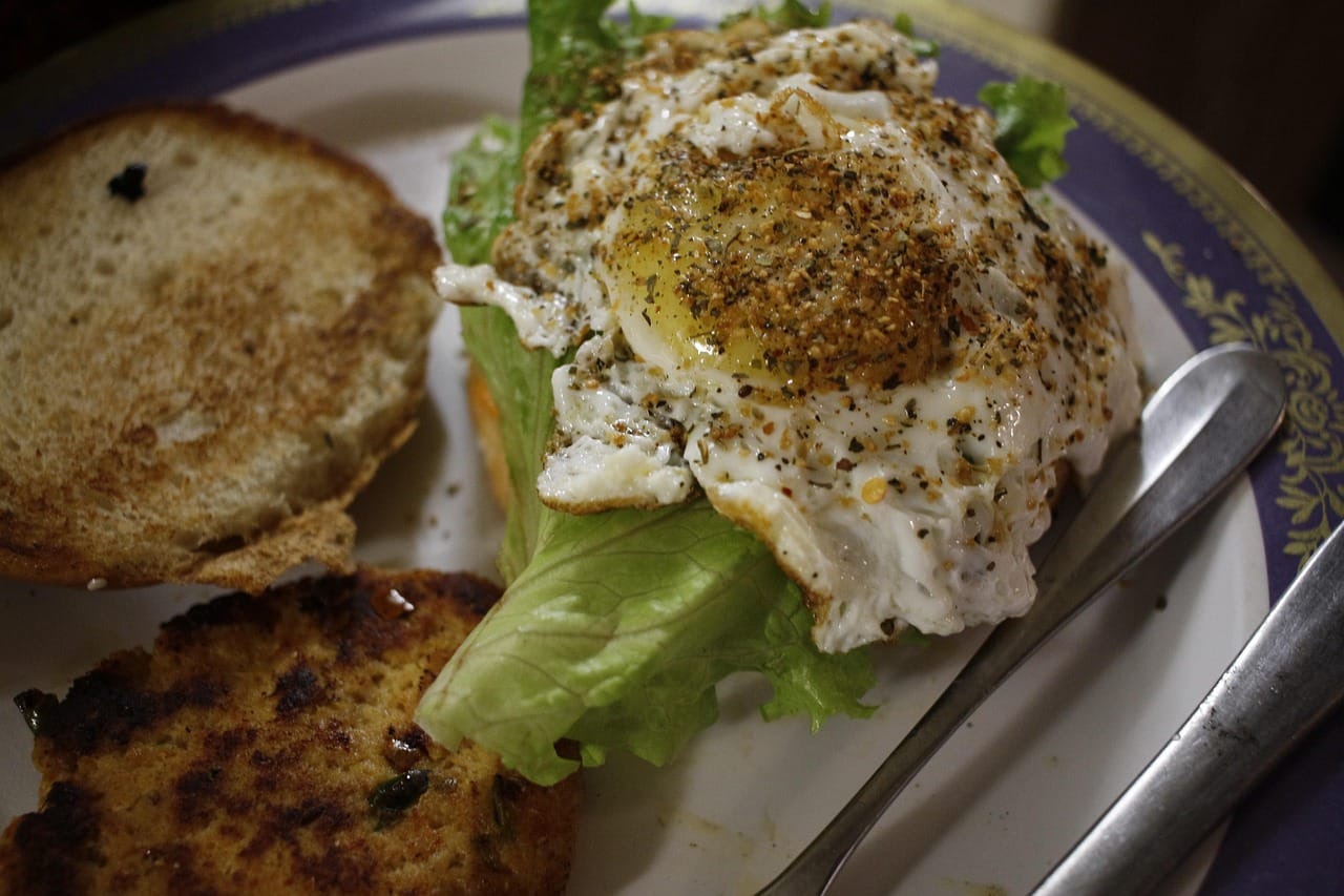 Grilled chicken breast, boiled eggs, and beans arranged on a plate