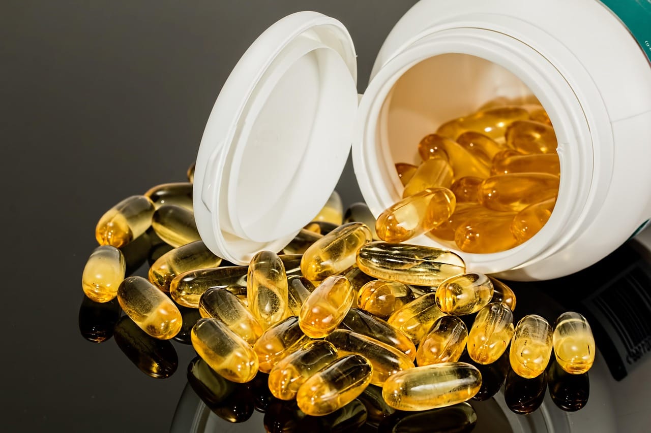 An open amber bottle spilling small tablets onto a countertop