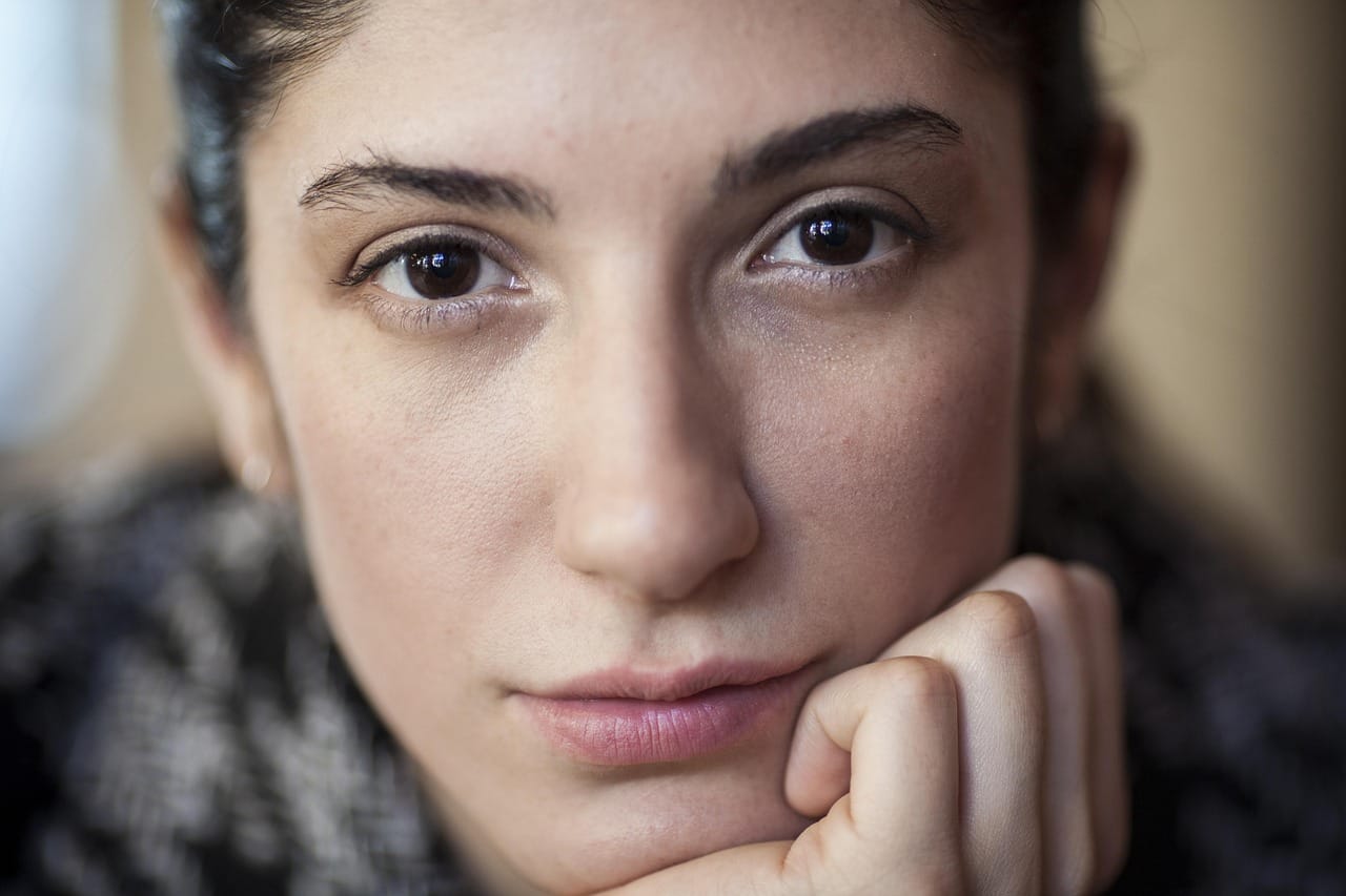 Close-up of a woman gently touching her clear glowing cheek