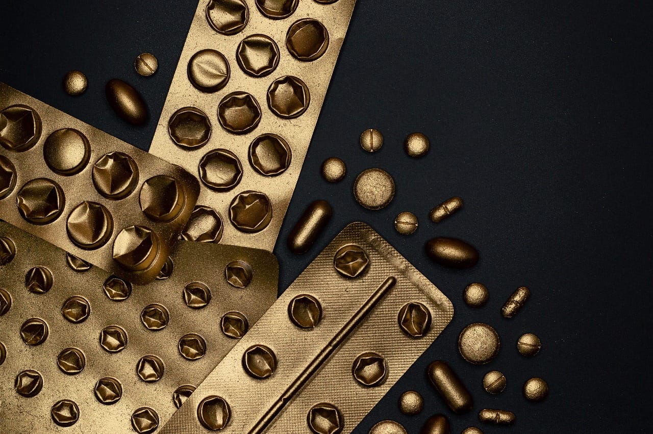 small golden softgel capsules spilling from a glass bottle
