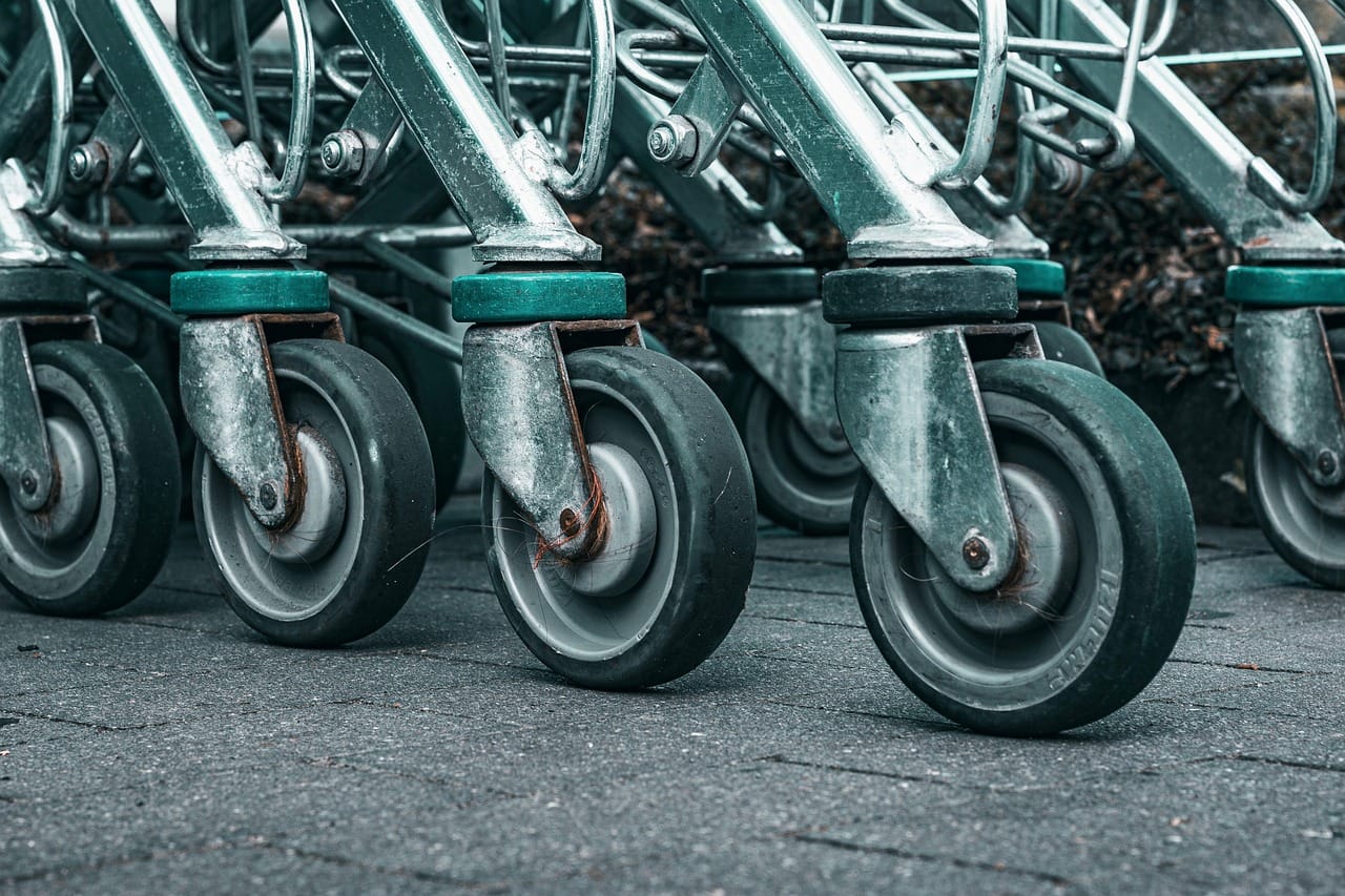 person pushing a cart down a supermarket produce aisle
