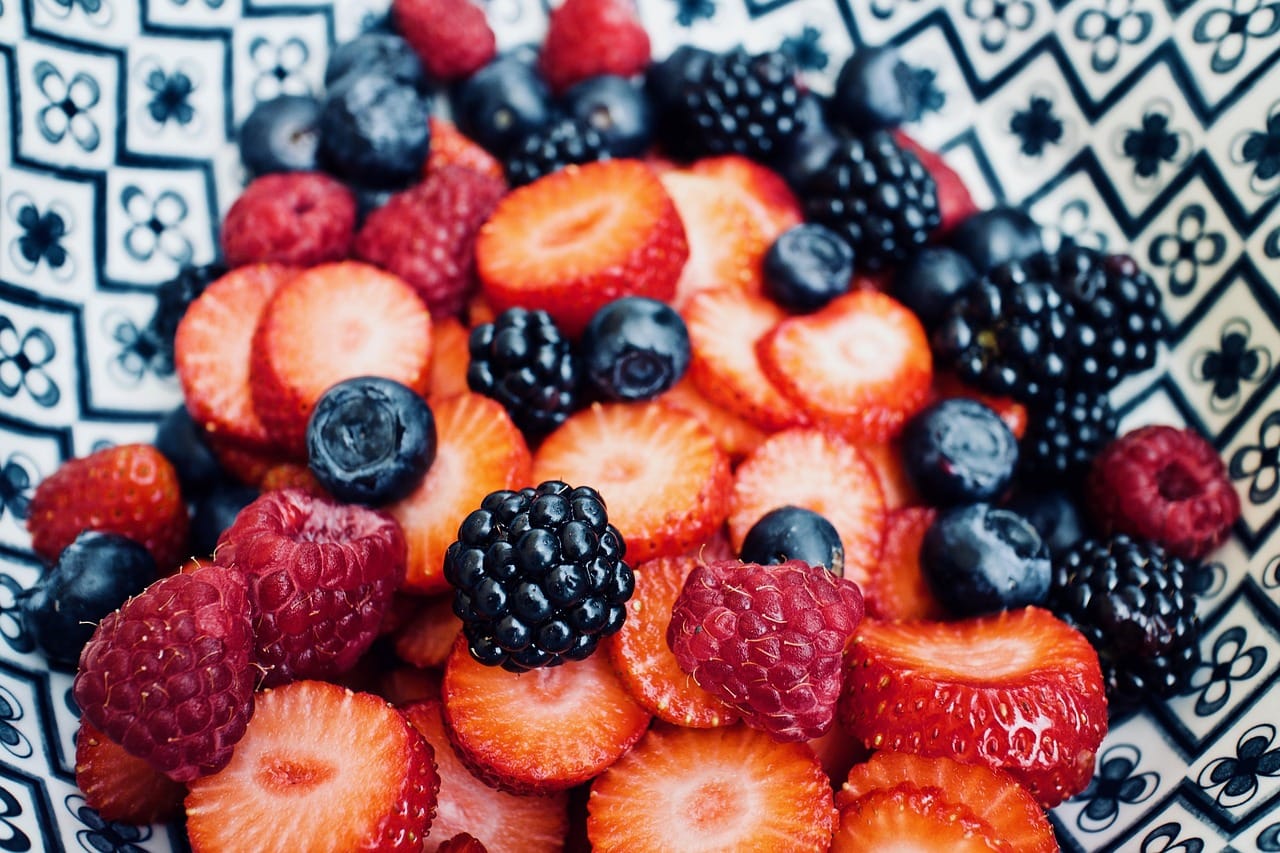 Fresh blueberries heaped in a white ceramic bowl on wood