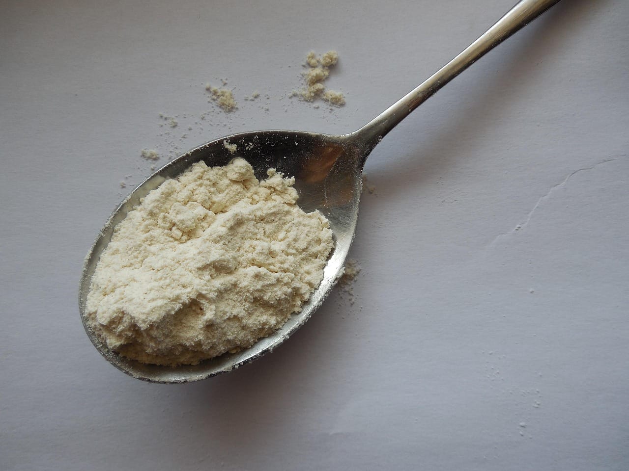 a hand scooping green powder with a small measuring spoon